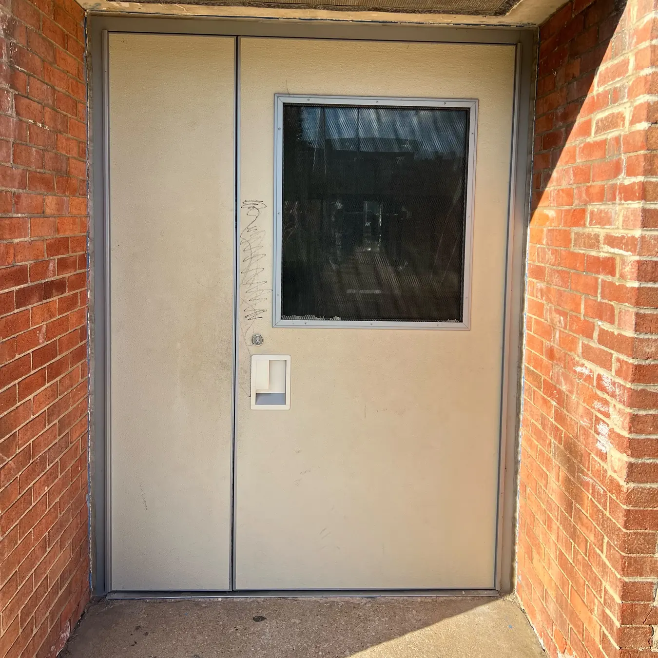 FRP commercial doors: exterior fiberglass door with vision panel and recessed pull in a brick entryway, Washington DC